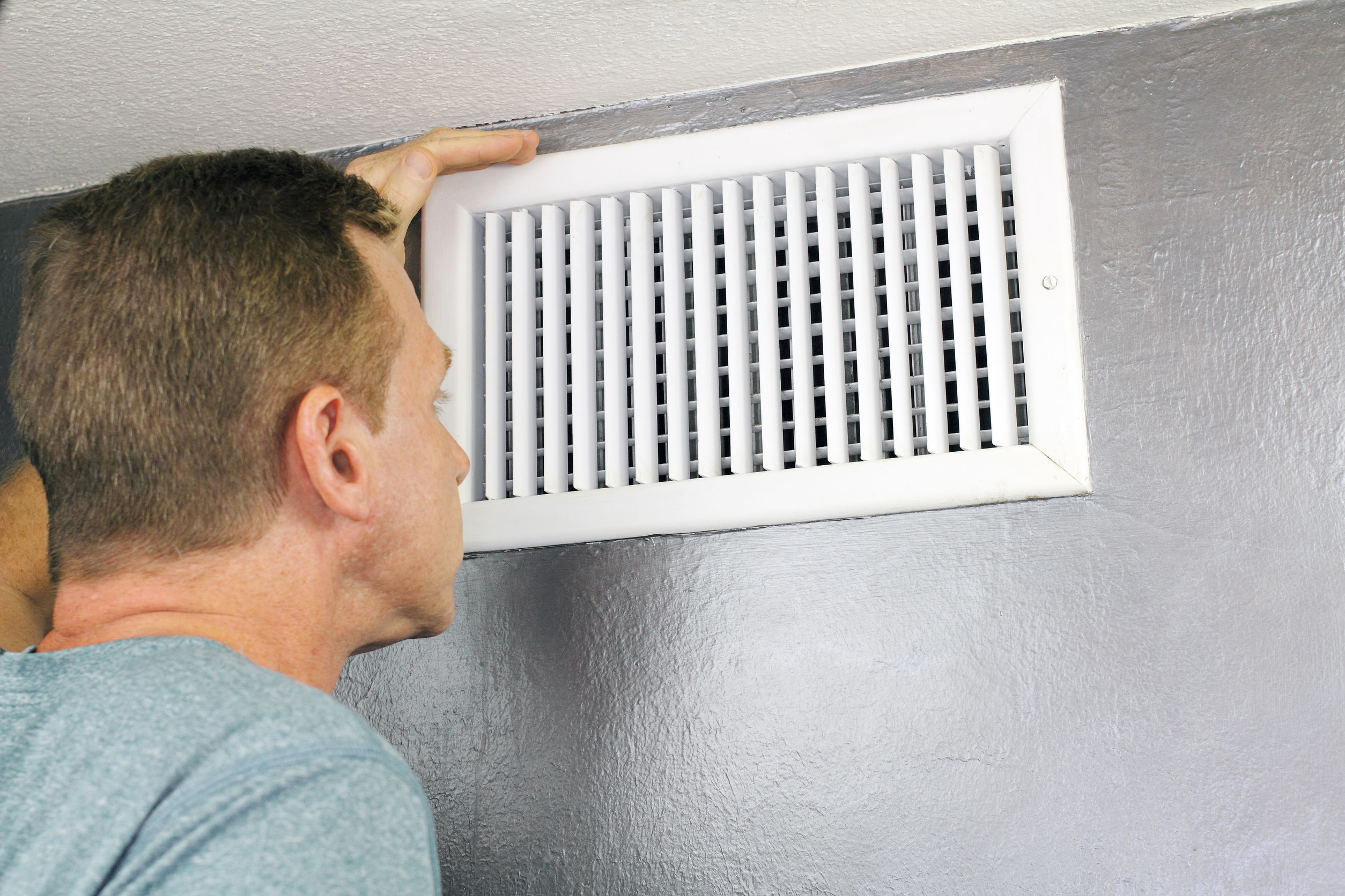 Man examining an air conditioning vent
