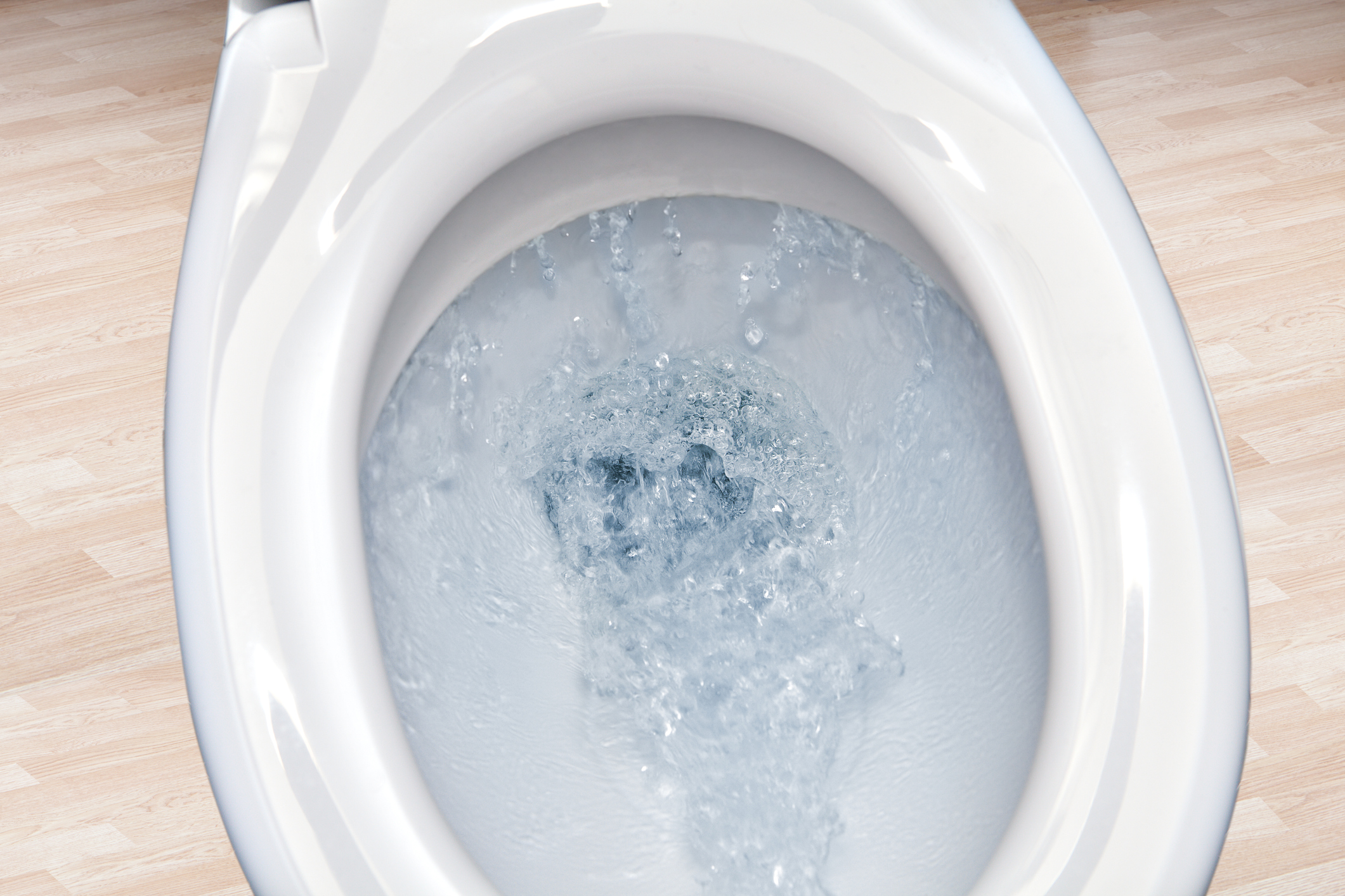 Closeup view of a flushing white toilet bowl.